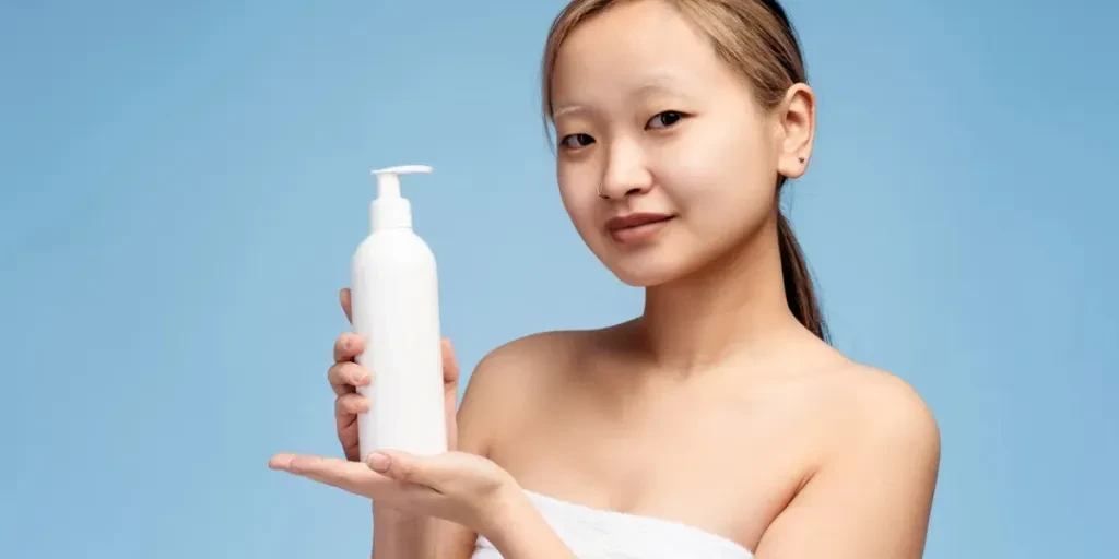 Portrait of beautiful Asian girl holding hair conditioner before applying