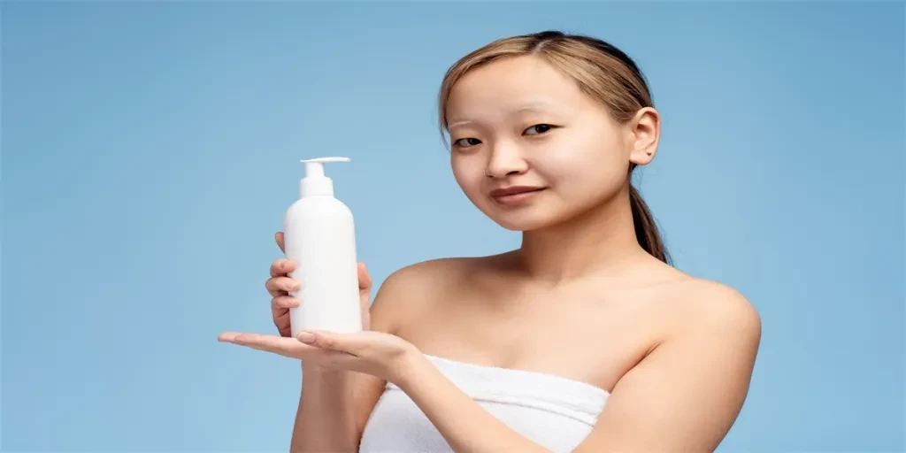 Portrait of beautiful Asian girl holding hair conditioner before applying