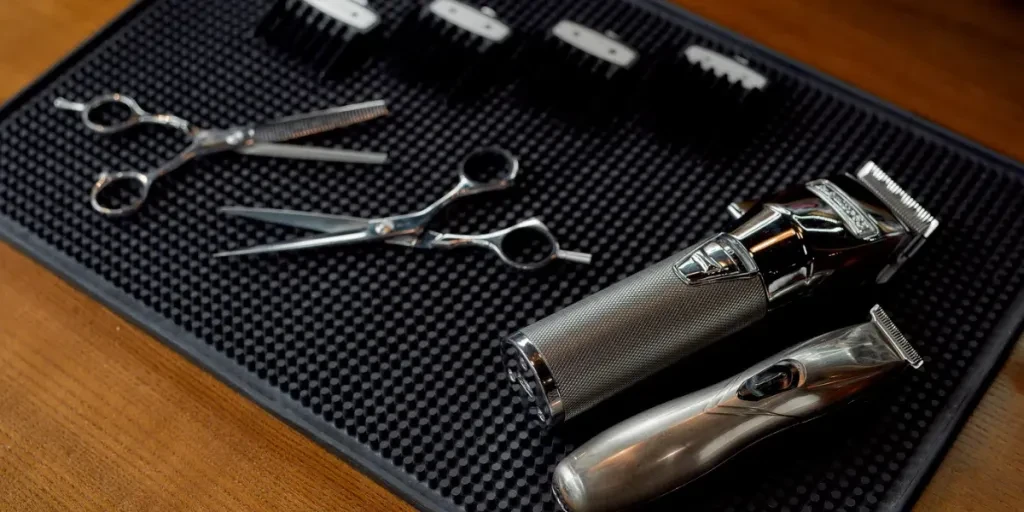 Scissors, electric hair trimmers and four different nozzles lying on a rubber mat in the barbershop