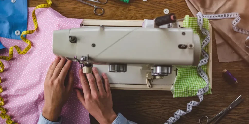 Seamstress using a sewing machine and various sewing accessories for clothes production during sewing process