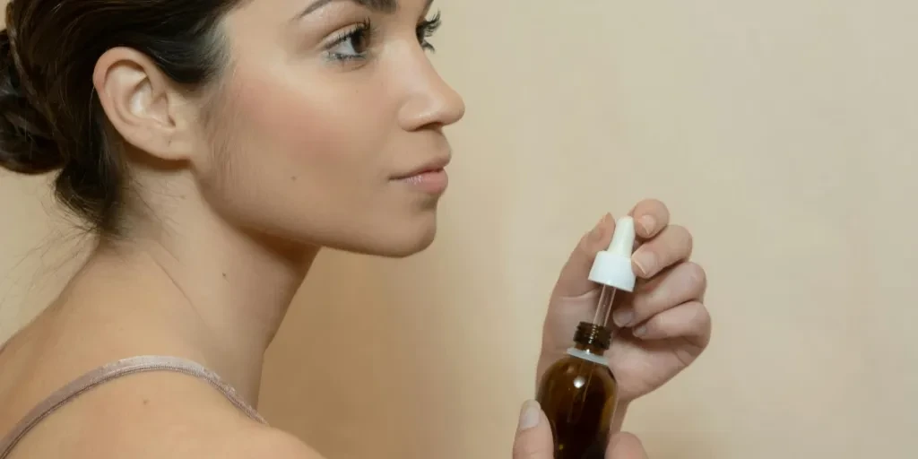 Side profile of a young woman holding a dropper bottle for skincare routine