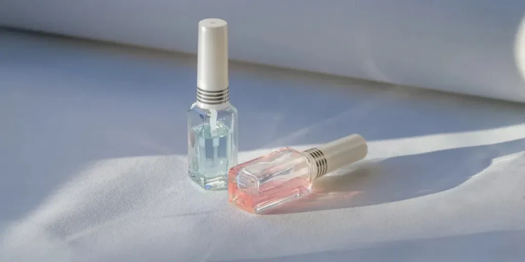 Small bottles of transparent lacquers for manicure placed on white sofa in sunlight