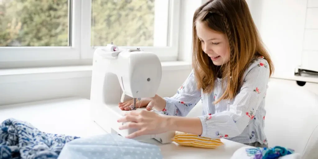 Smiling Little Girl At The Table With Sewing Machinen