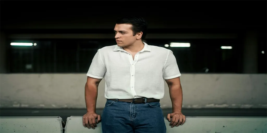 Stylish man in casual attire with white shirt and jeans in an urban backdrop by Oktay