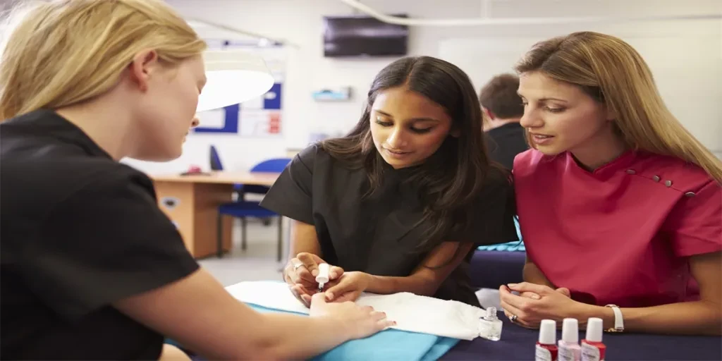 Teacher Helping Students Training To Become Beauticians Painting Nails