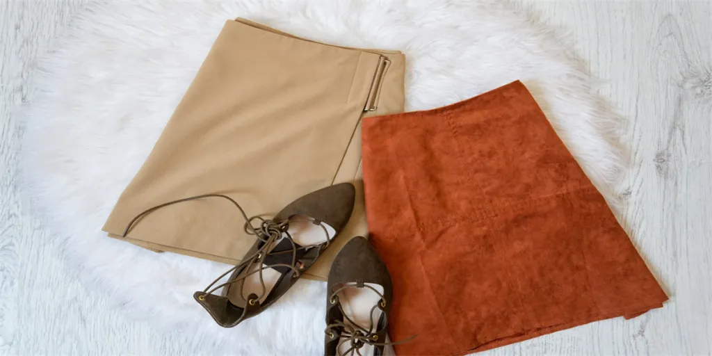 Two brown suede skirt and shoes on a white fur