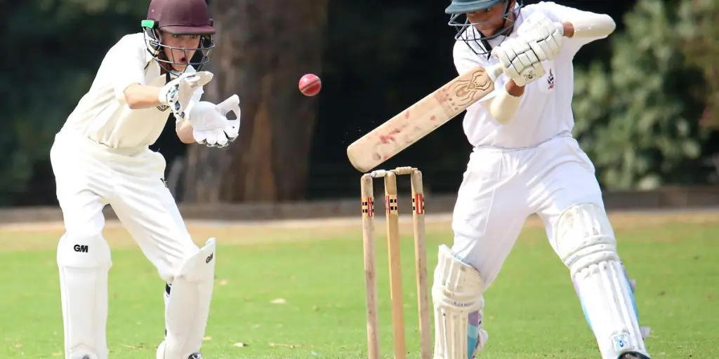 Two cricket players in action on a sunny day, showcasing skillful batting and wicket-keeping