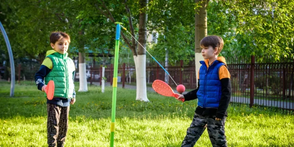 Two friends are playing tetherball swing ball game in summer camping