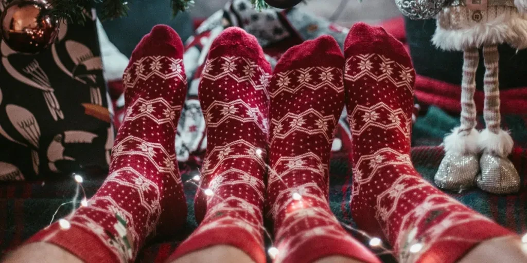 Two people in holiday socks relaxing by a Christmas tree