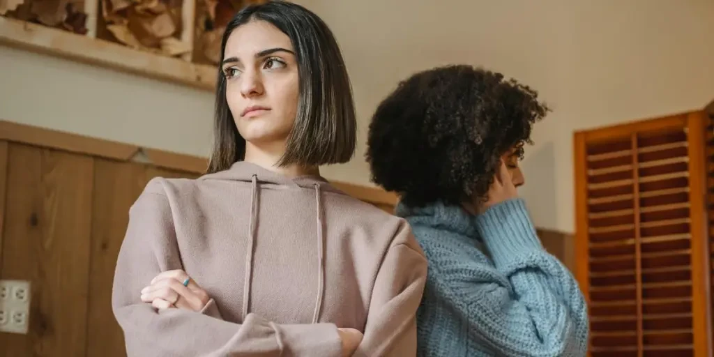 Two women facing away from each other, appearing upset in a home setting