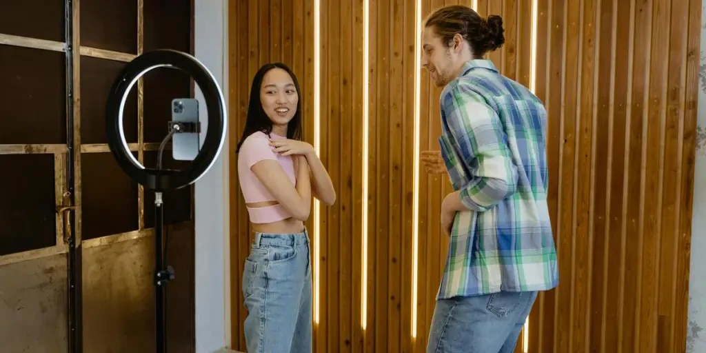 Two young adults having fun dancing in front of a phone camera indoors