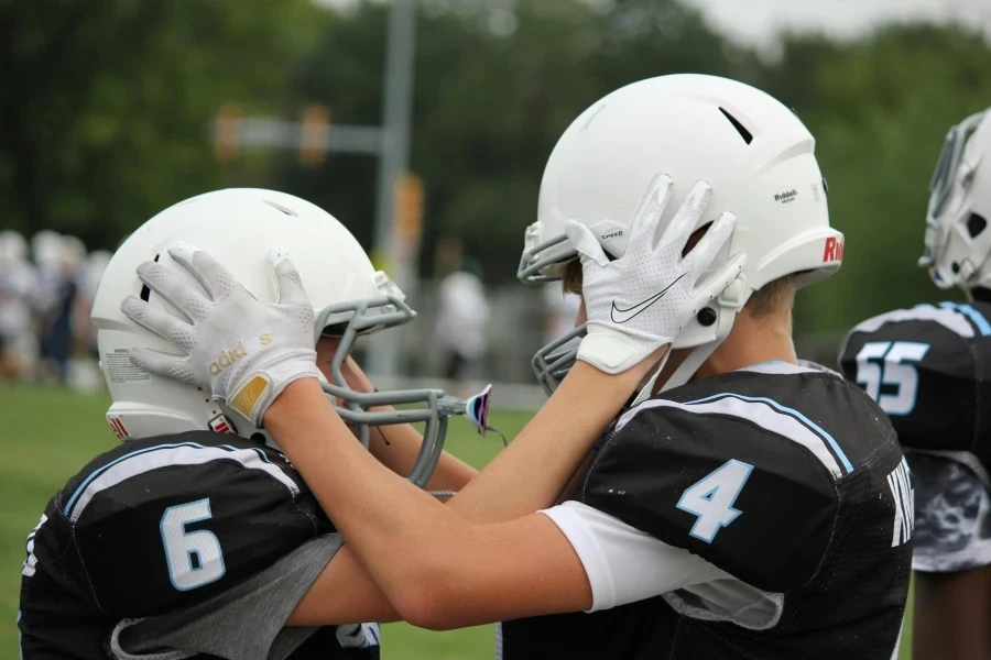 Two young football players in helmets and gear motivate each other before a match