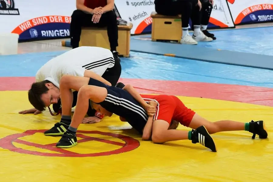 Two young wrestlers engage in a competitive match during an indoor sports event