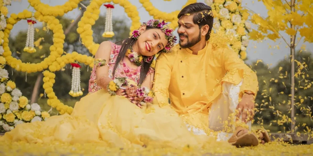 Vibrant Indian couple enjoying a traditional Haldi ceremony with yellow floral decor