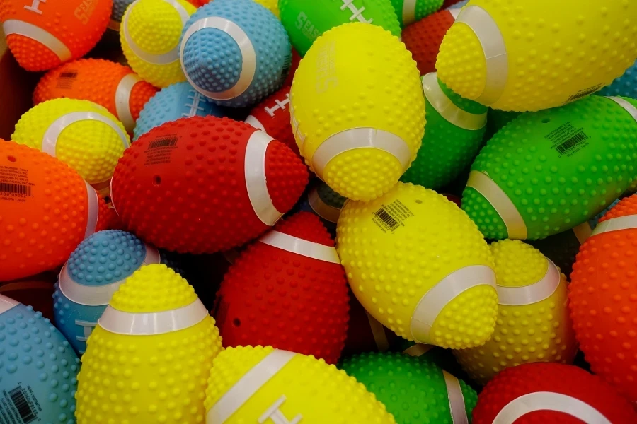 Vibrant pile of colorful, textured plastic toy footballs for games and recreation