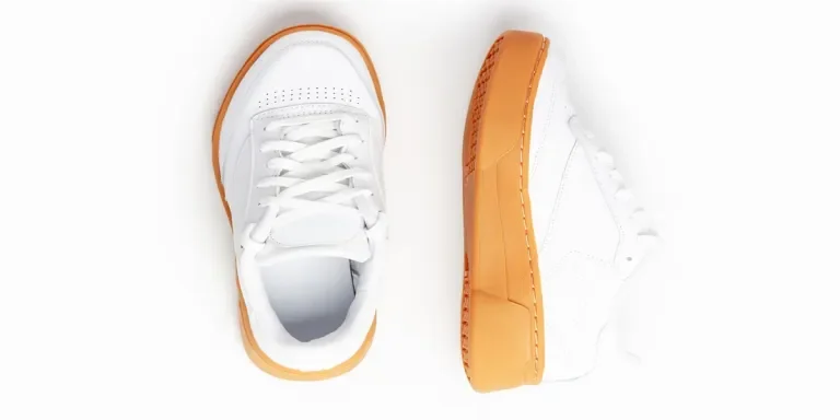 White sneaker with brown sole on white background close up, top view