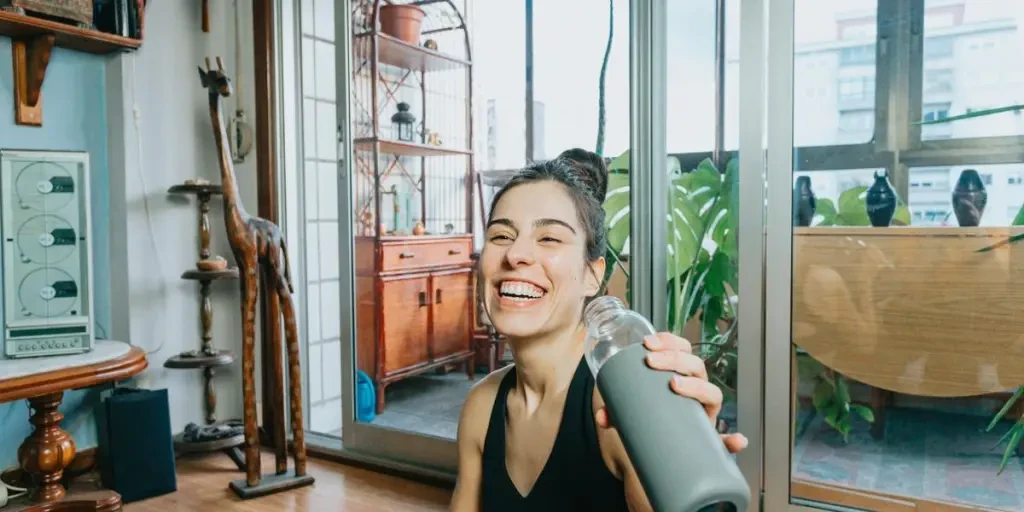 Woman Laughs And Holds Up Water Bottle To Drink