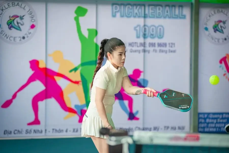 Woman actively engaged in a game of pickleball indoors in Hanoi, Vietnam