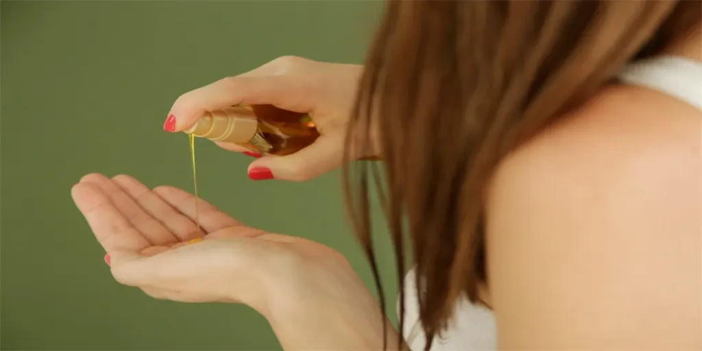 Woman applying oil on hair ends, split hair tips