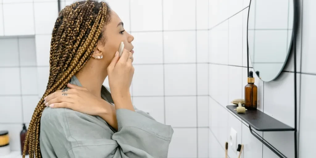 Woman applying skincare in a bathroom while looking at the mirror, focusing on self-care 