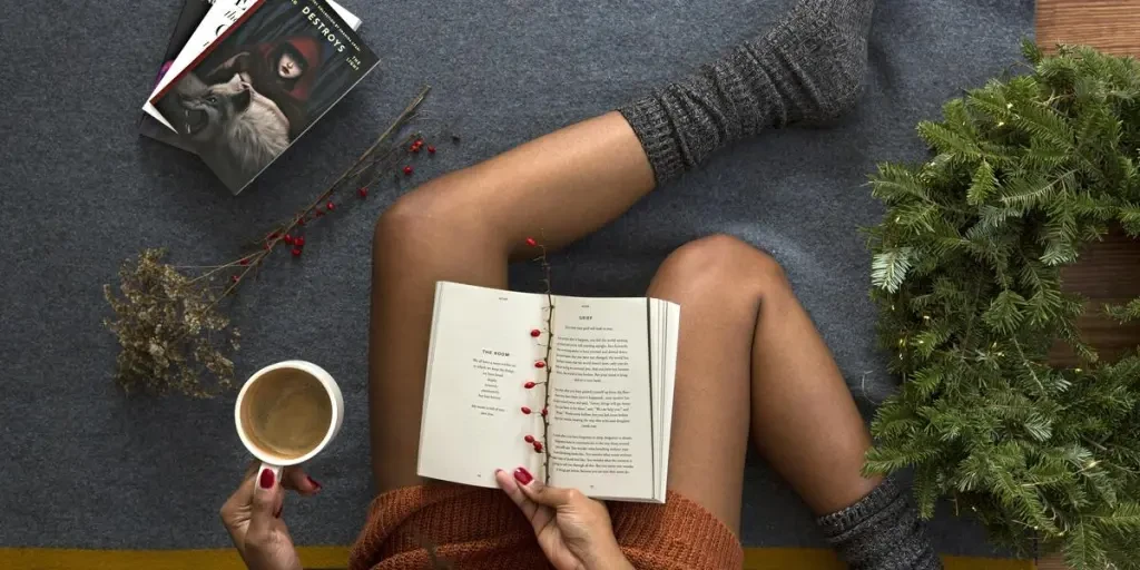 Woman reads book while drinking coffee for holiday