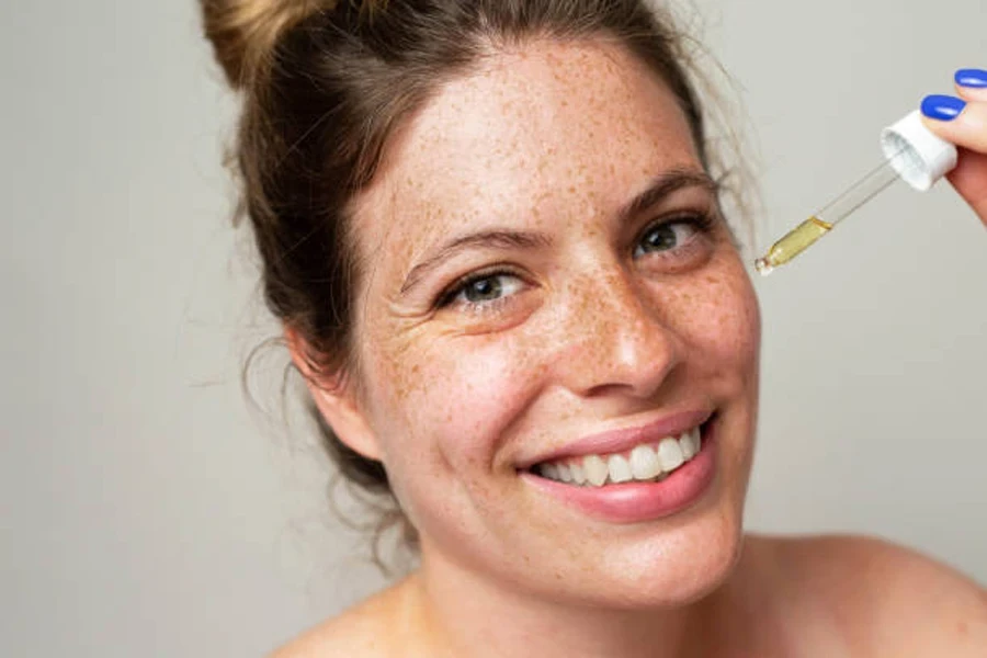 Woman smiling while applying retinol serum to face