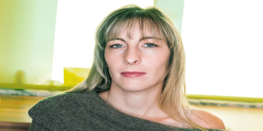 Woman with a wool sweater and bare shoulder looks demanding at the camera