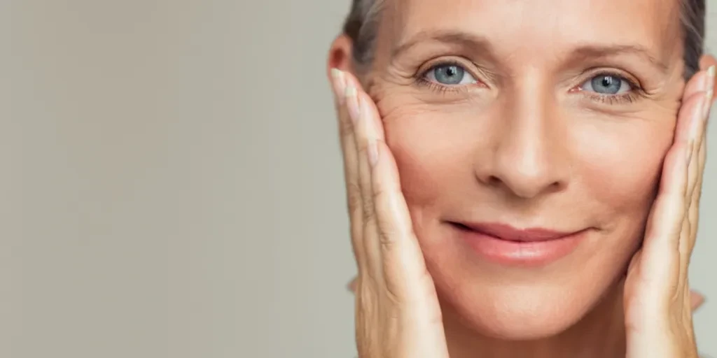 Woman with crows feet holding sides of face with hands