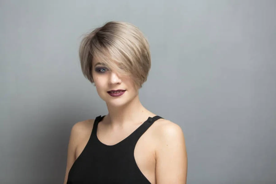 Woman with short pixie haircut dyed dark blond with bangs