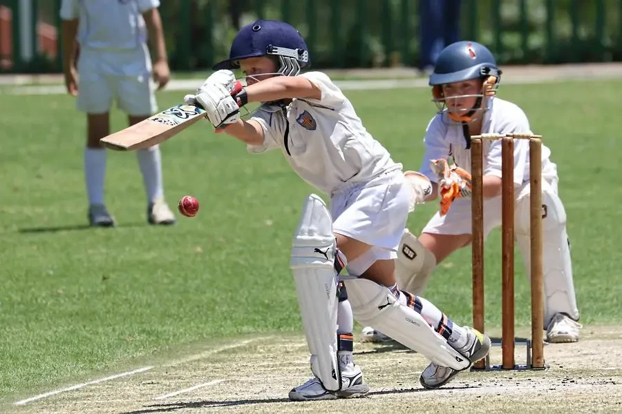 Young cricketers playing with focus and skill on a sunny outdoor field