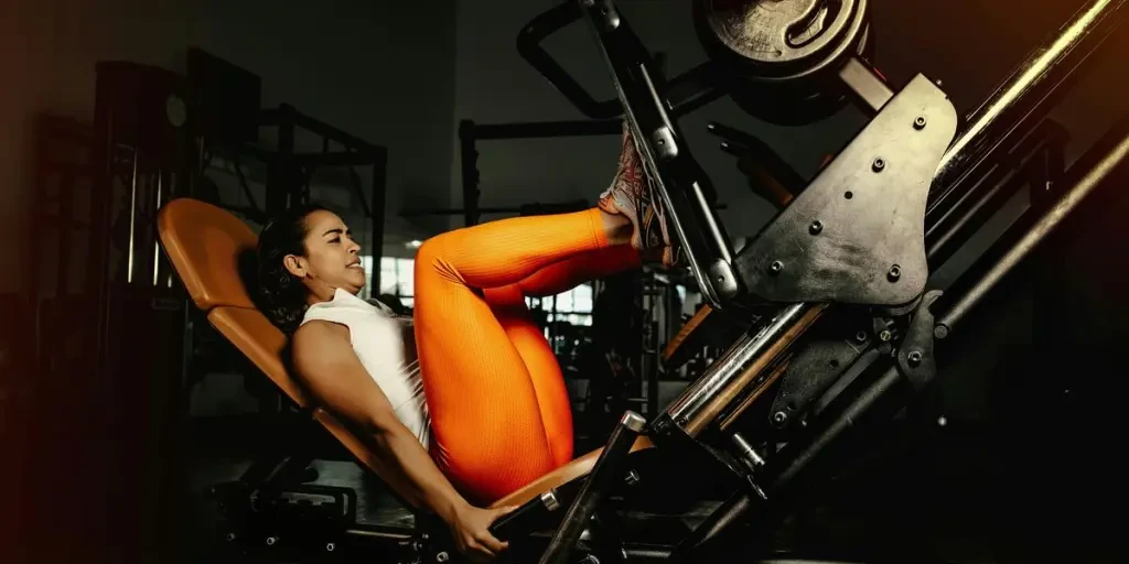 Young woman performing leg press exercise in a gym setting, showcasing strength and fitness