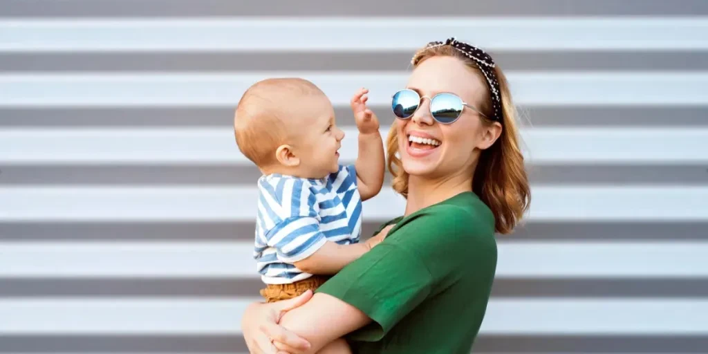 Young woman with a baby boy standing against the wall