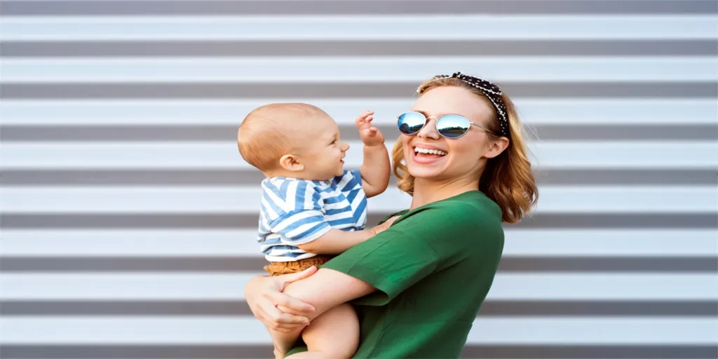 Young woman with a baby boy standing against the wall