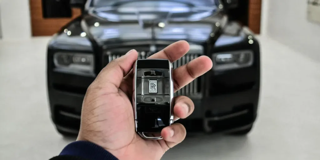 La mano de un hombre con un mando a distancia activa el sistema de alarma del coche.