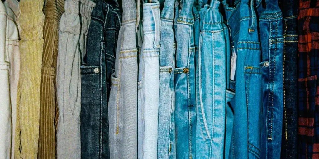 a rack of different colored jeans hanging from hooks