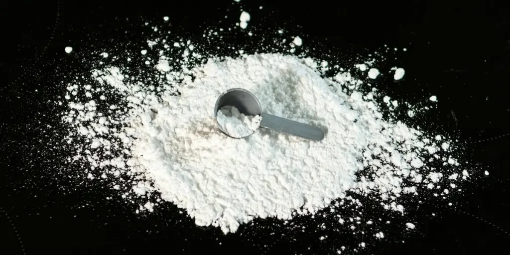 a scoop of powder next to a scoop of sugar