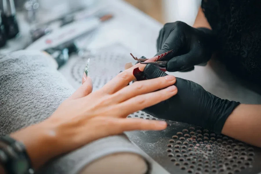 Beautician attaching long nails in salon