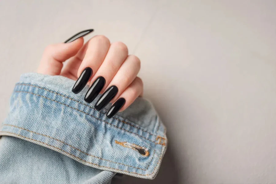 Black coffin nails next to jean jacket cuff