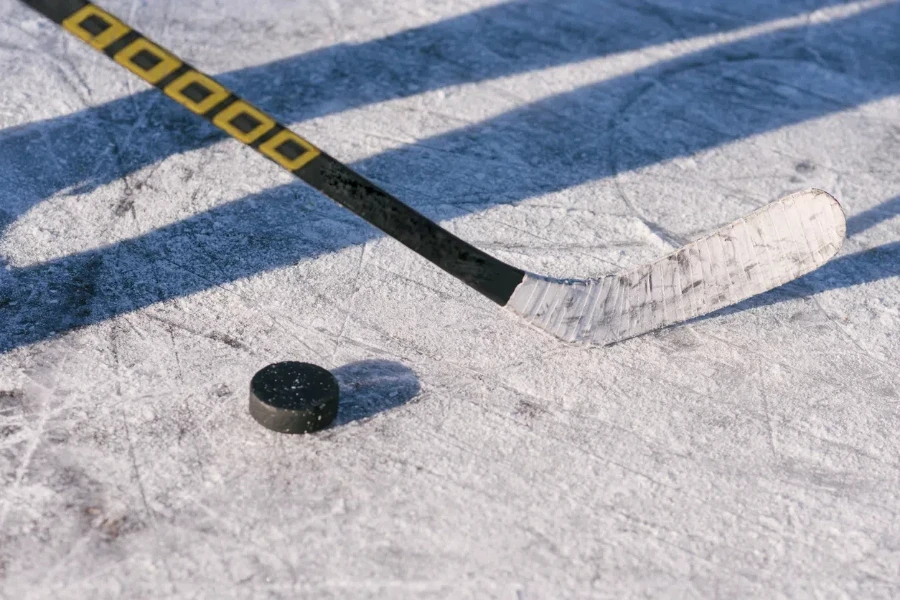 close-up stick and puck on the ice background