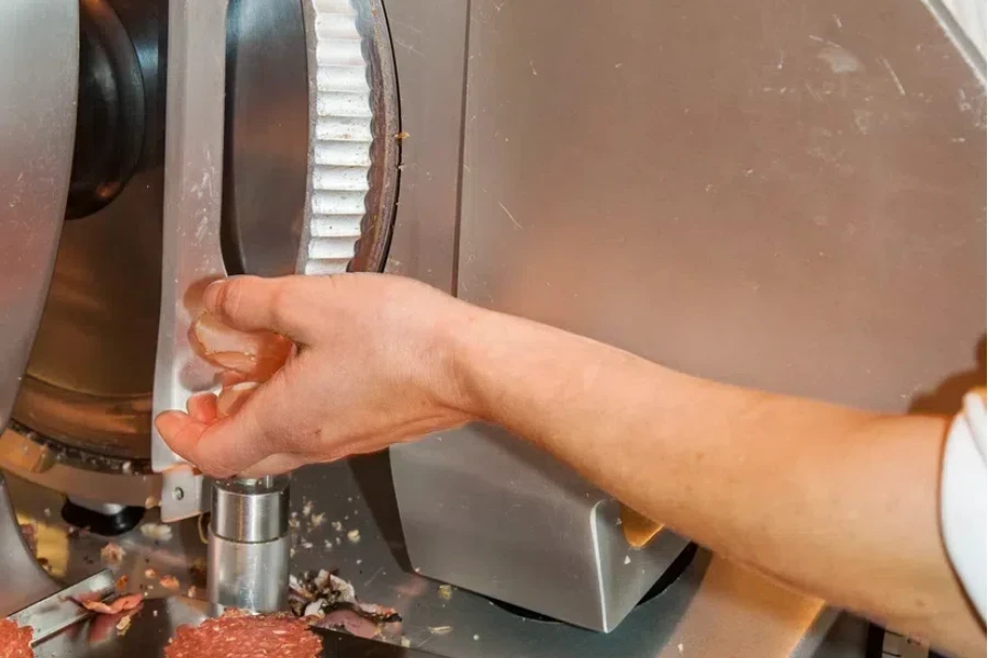 detail of woman cutting a sausage into slices with the cutting machine