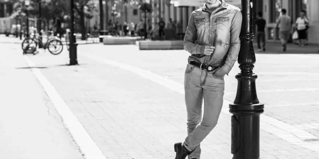 fashion young man leaning against the street lamp