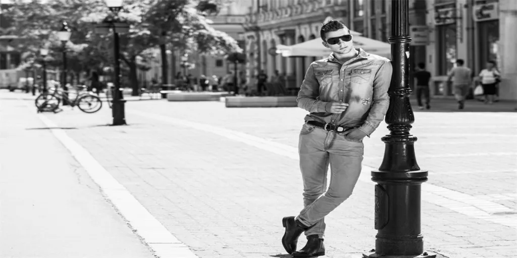 fashion young man leaning against the street lamp