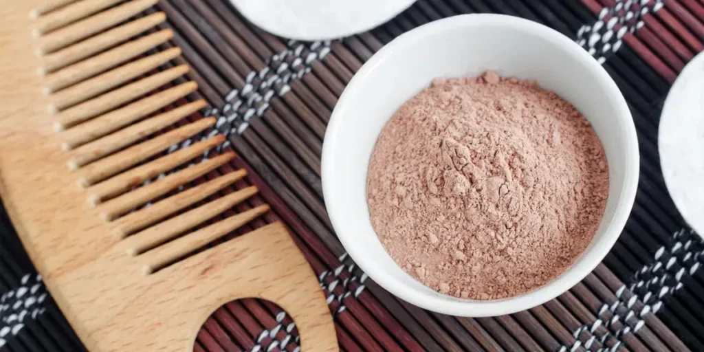 ink bentonite clay powder in the small white bowl and hair brush