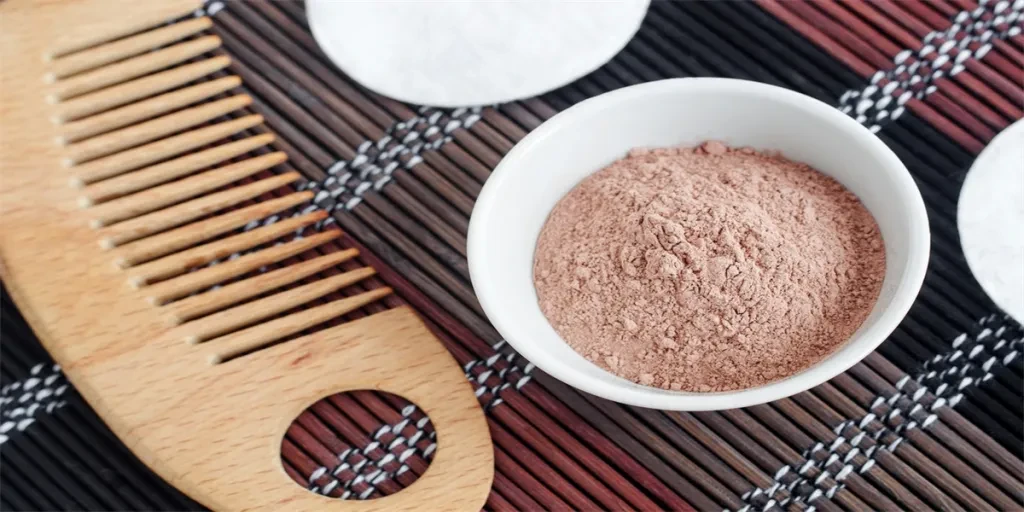 ink bentonite clay powder in the small white bowl and hair brush