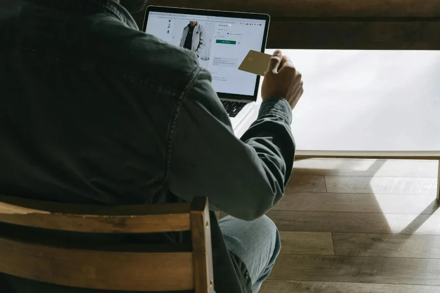 Person holding card while using laptop