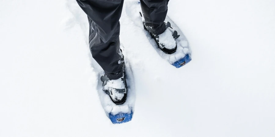 person standing in fresh snow with snowshoes