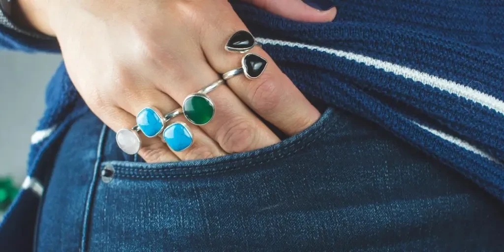 person wearing silver teal and green gemstone ring