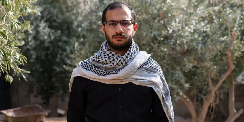 portrait for male wearing keffiyeh in olive tree field with black background and black shirts also with angry facial expression