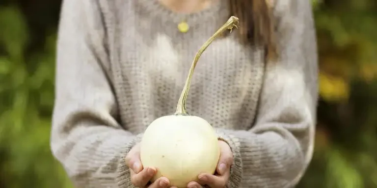 woman holding white round fruit outdoor