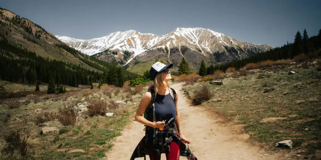 woman walking on brown road holding camera